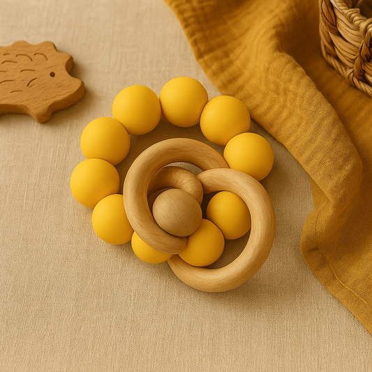 Yellow silicone beaded baby teether with natural beechwood rattle rings on a warm neutral fabric.
