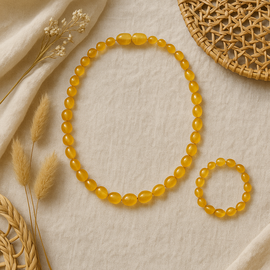 Boho-style honey amber baby teething necklace and matching bracelet set displayed on neutral linen with natural woven and dried floral accents.